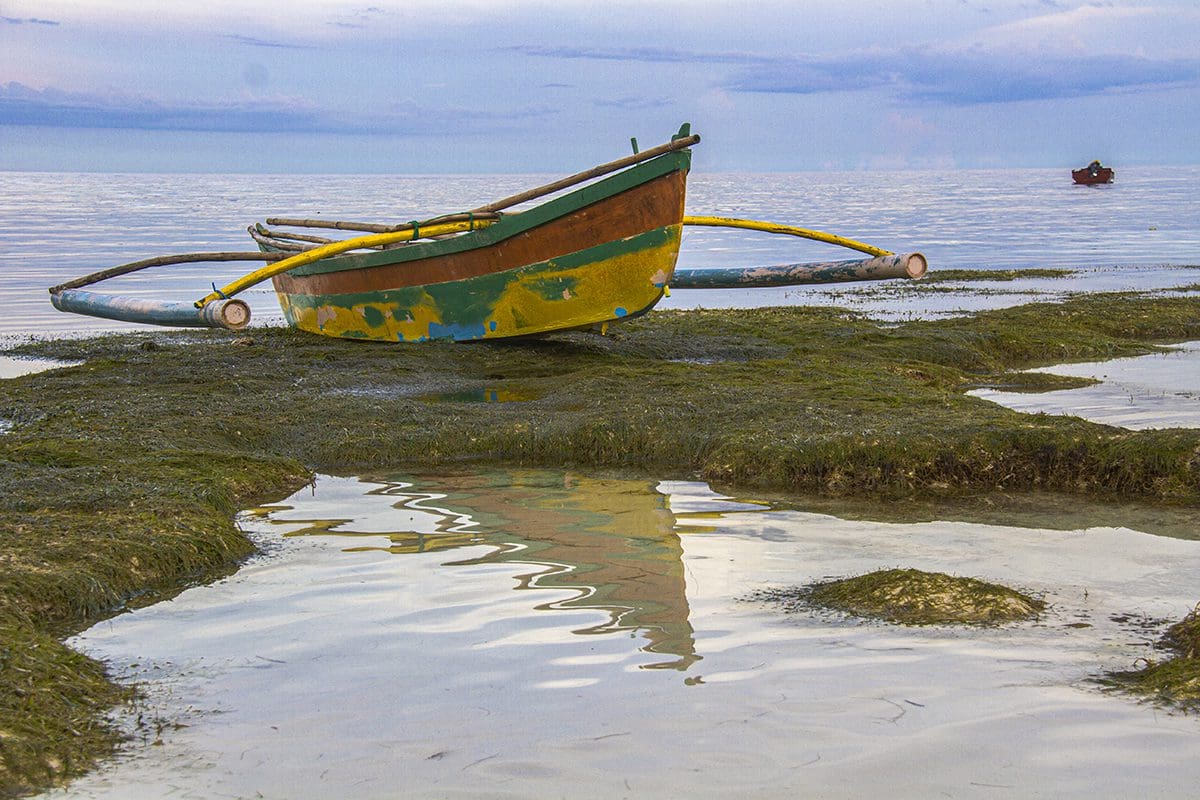 A boat sits on the shore of a body of water.