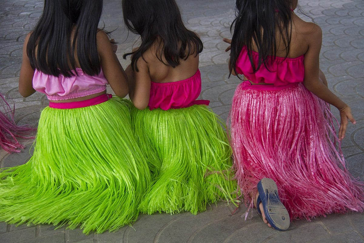 Hawaiian hula girls in green and pink hula skirts.