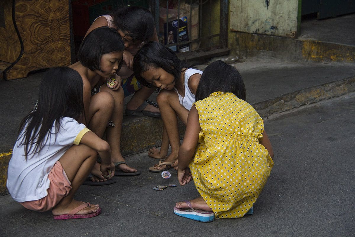 A group of girls playing with a coin on the street.