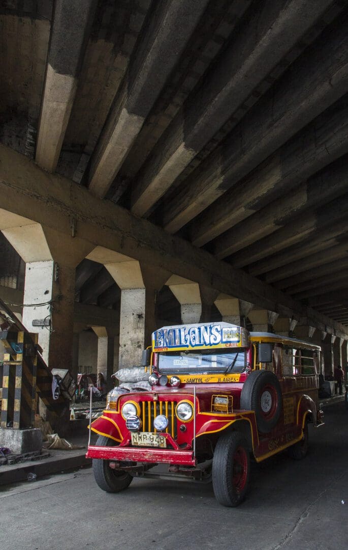 A red and white jeep parked under an overpass.