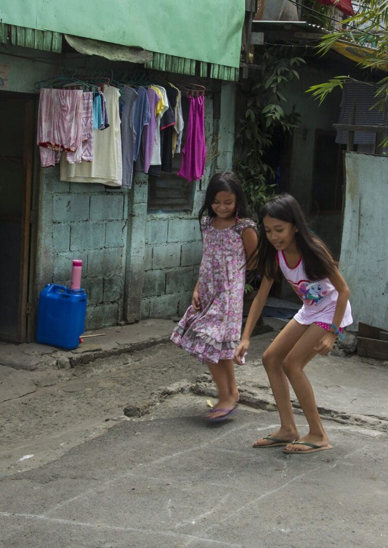 Two girls playing frisbee in the street.