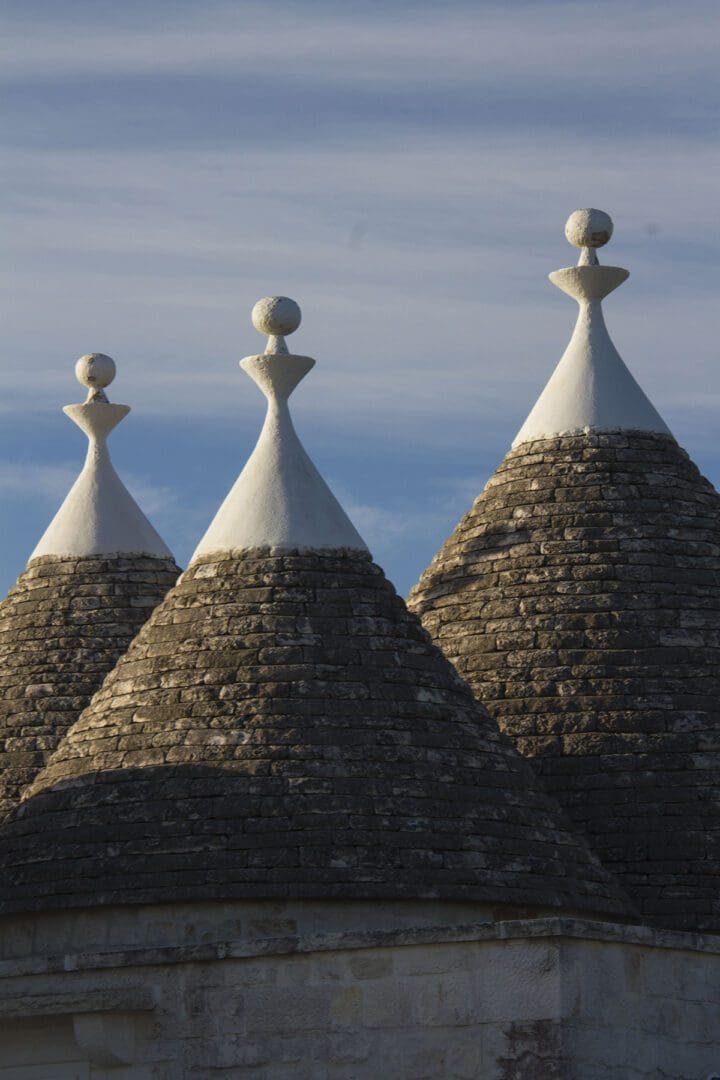 Three trulli roofs on a building with a blue sky.