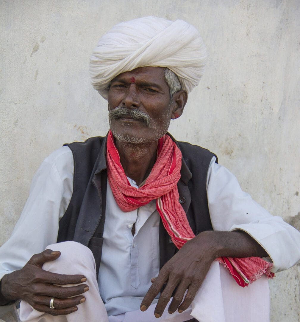 A man sitting on a bench with a turban on his head.