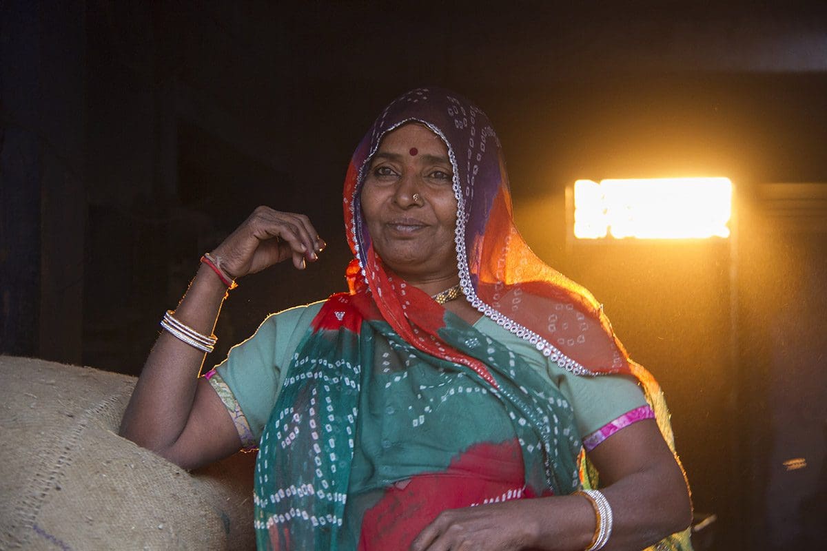 An indian woman sitting next to a bag of coffee.