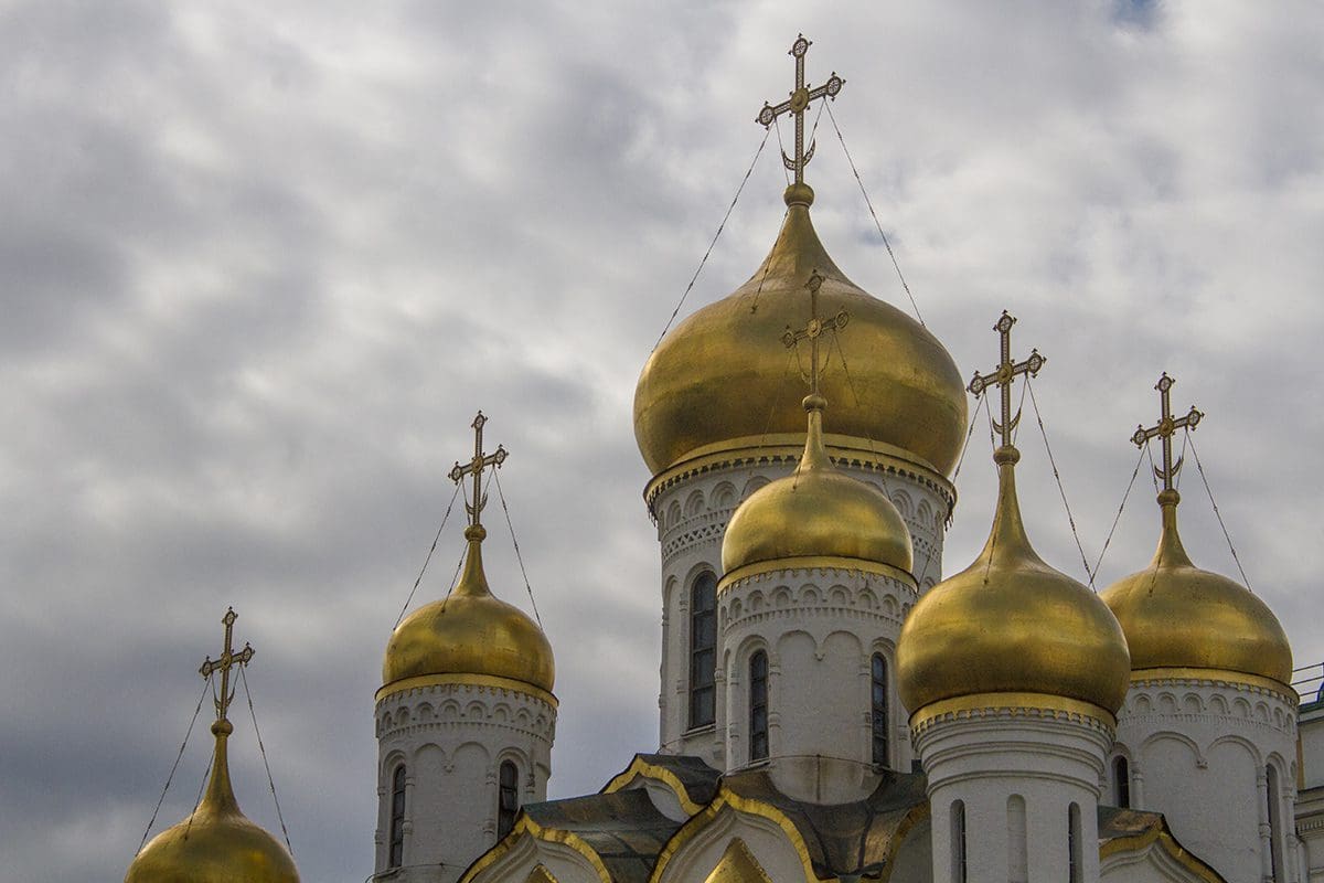 The golden domes of a church against a cloudy sky.