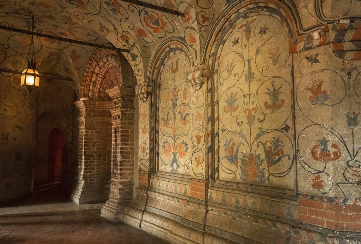 A hallway in a castle with ornate wall paintings.