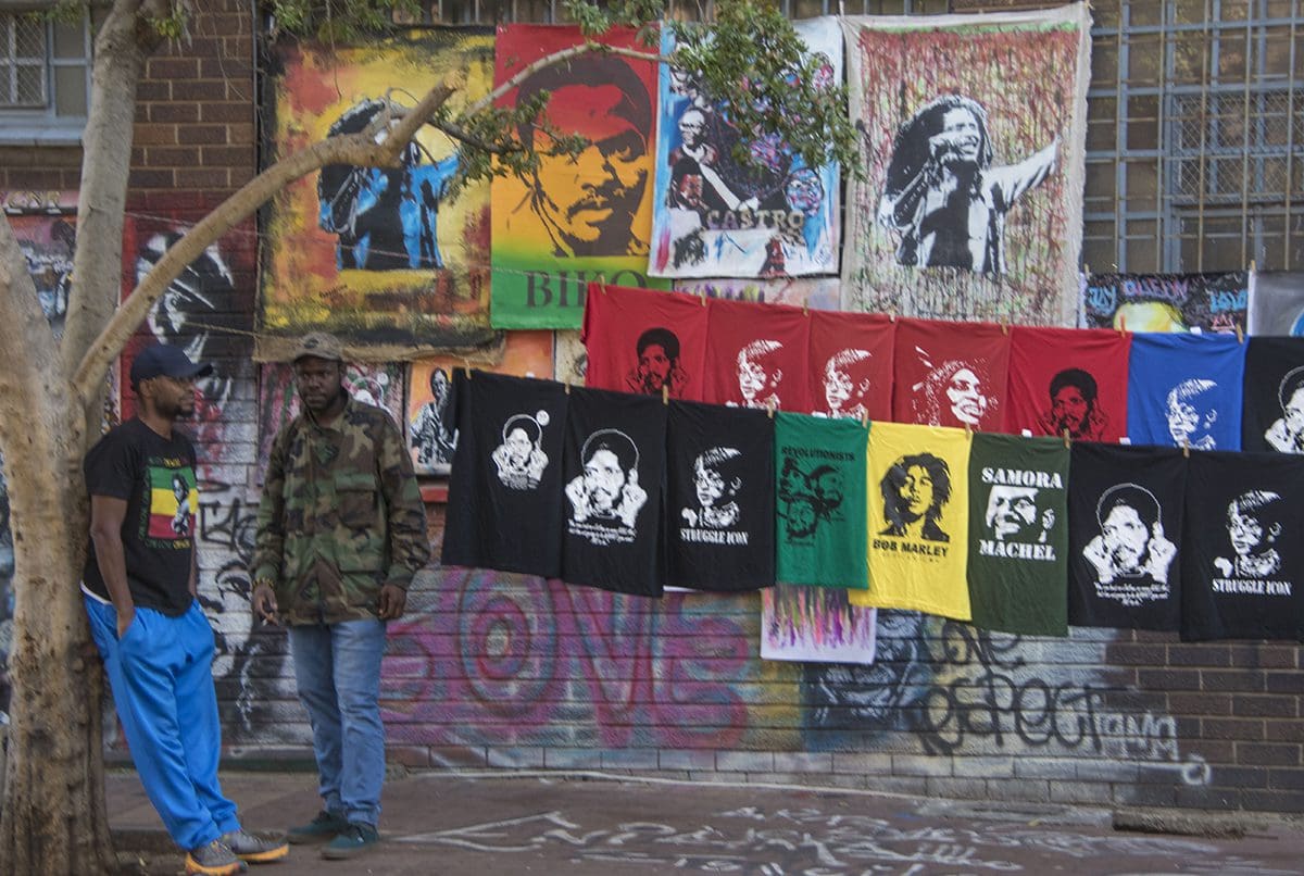 A group of people standing in front of a wall of t - shirts.