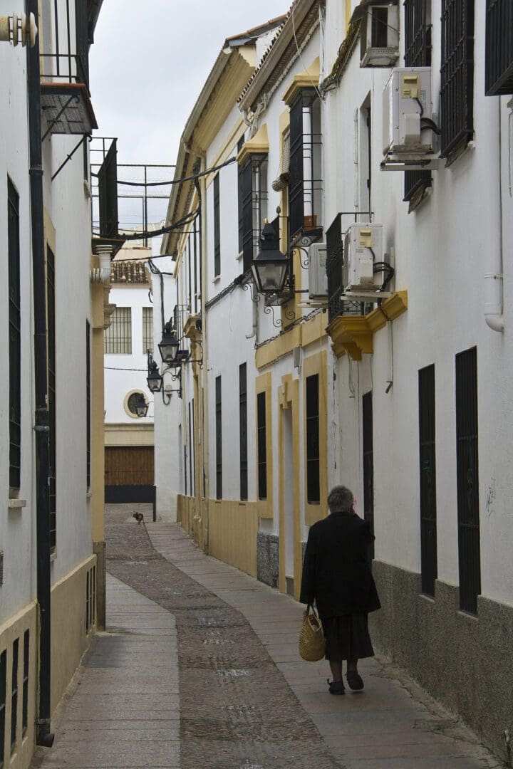 A woman walking down a narrow street.