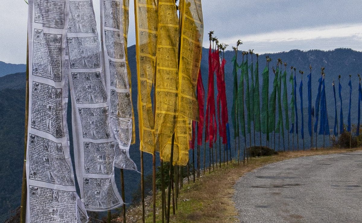 A line of colorful flags on a road in the mountains.