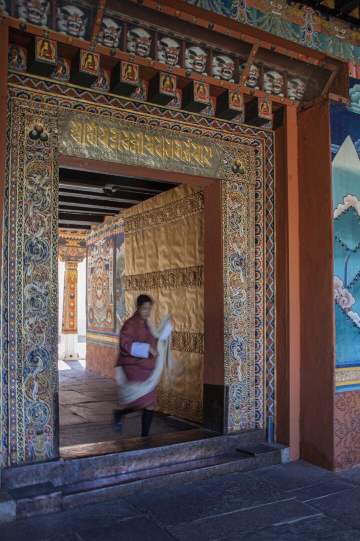 A woman walks through the door of a buddhist temple in bhutan.