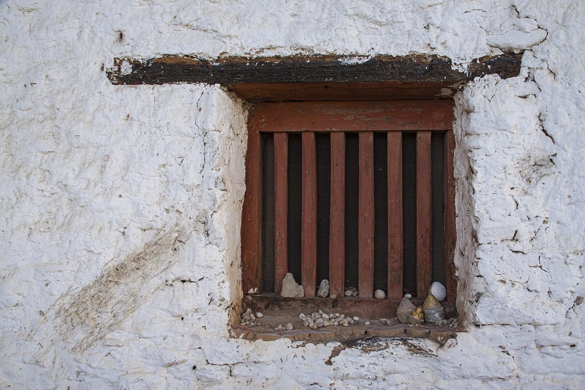 A window in a white building with wooden bars.