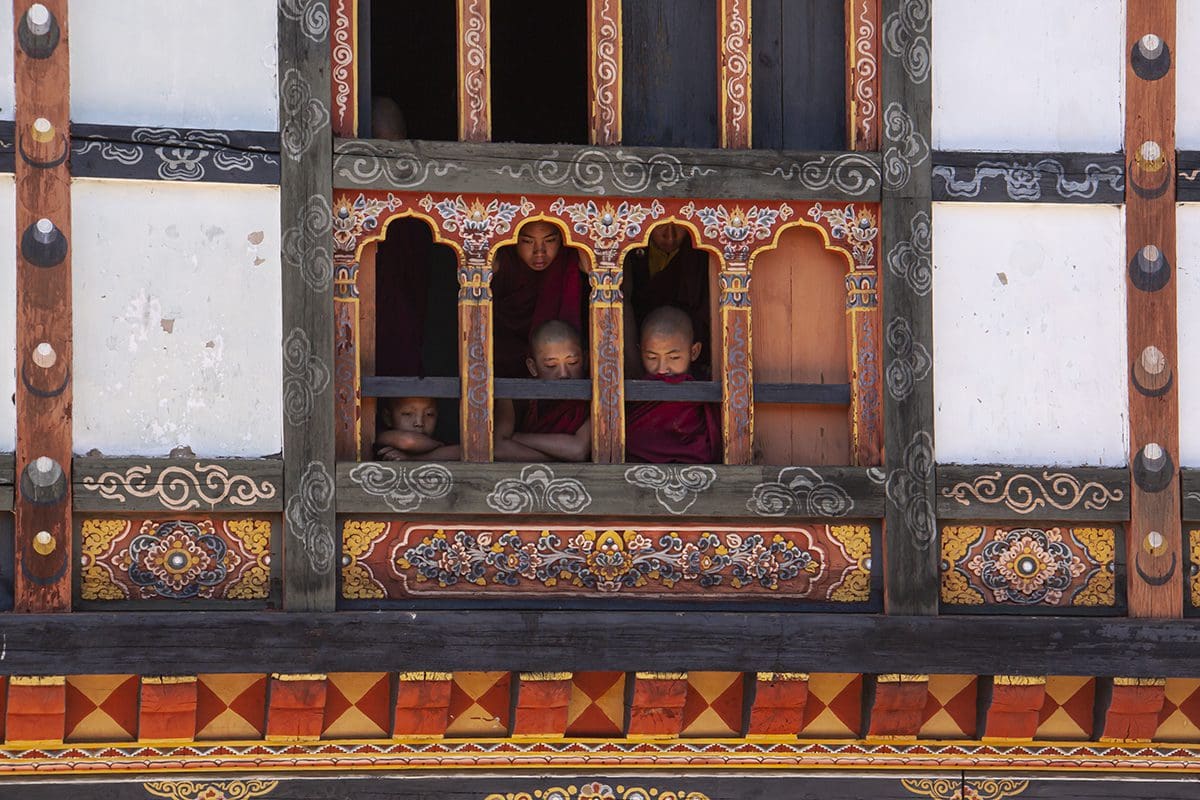 A group of young monks looking out of a window.