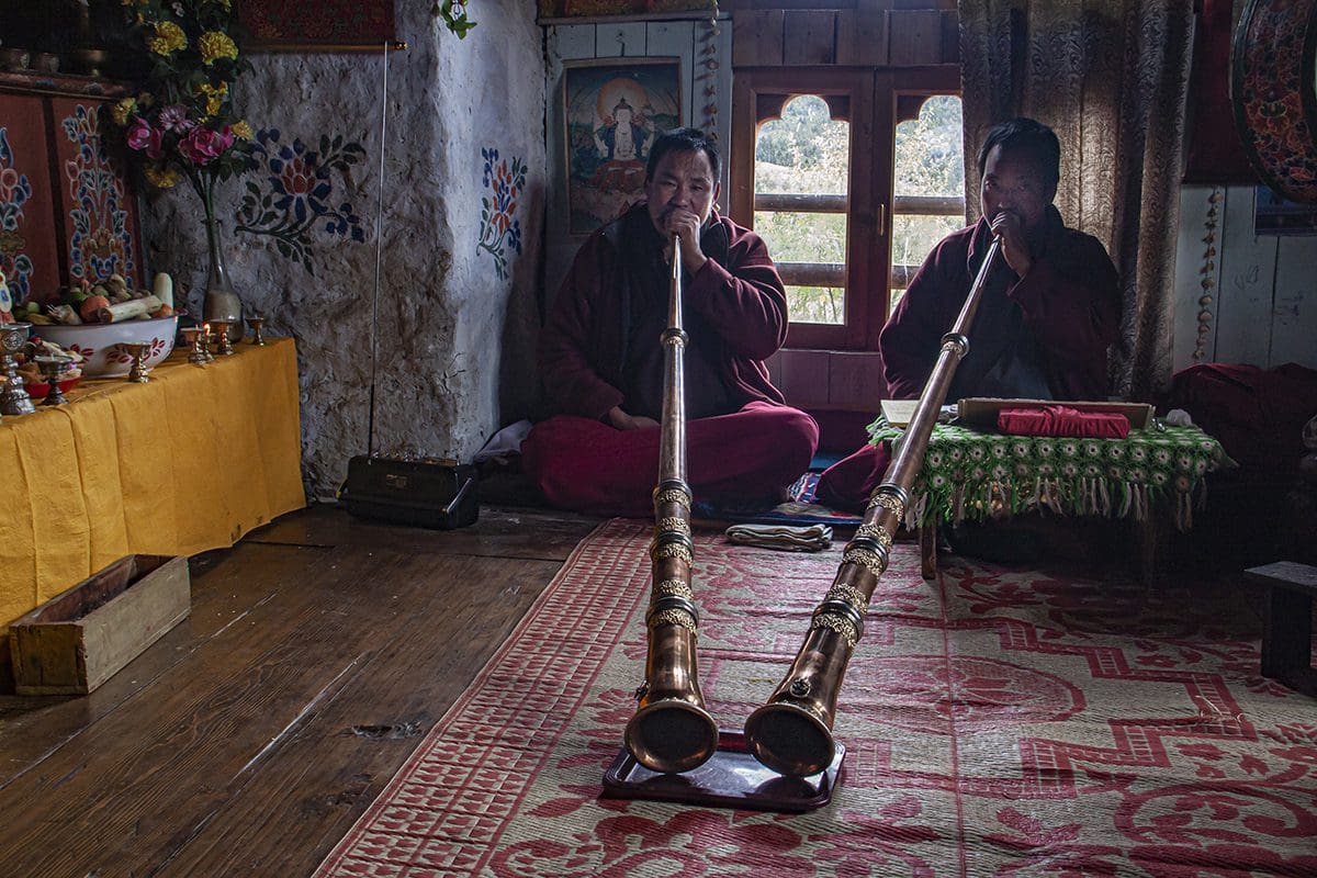 Two buddhist monks playing a flute in a room.