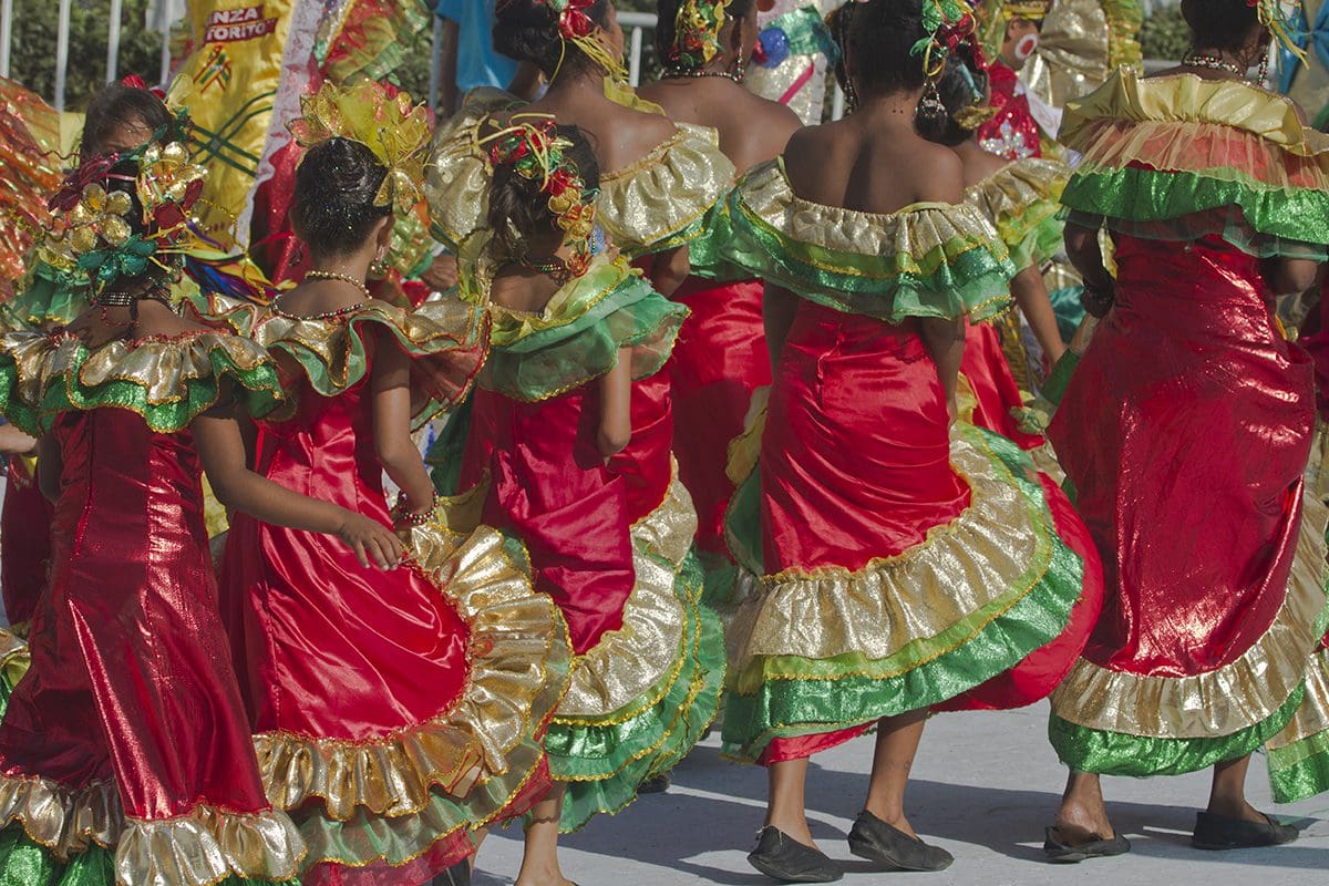 A group of women in colorful costumes are dancing in a parade.