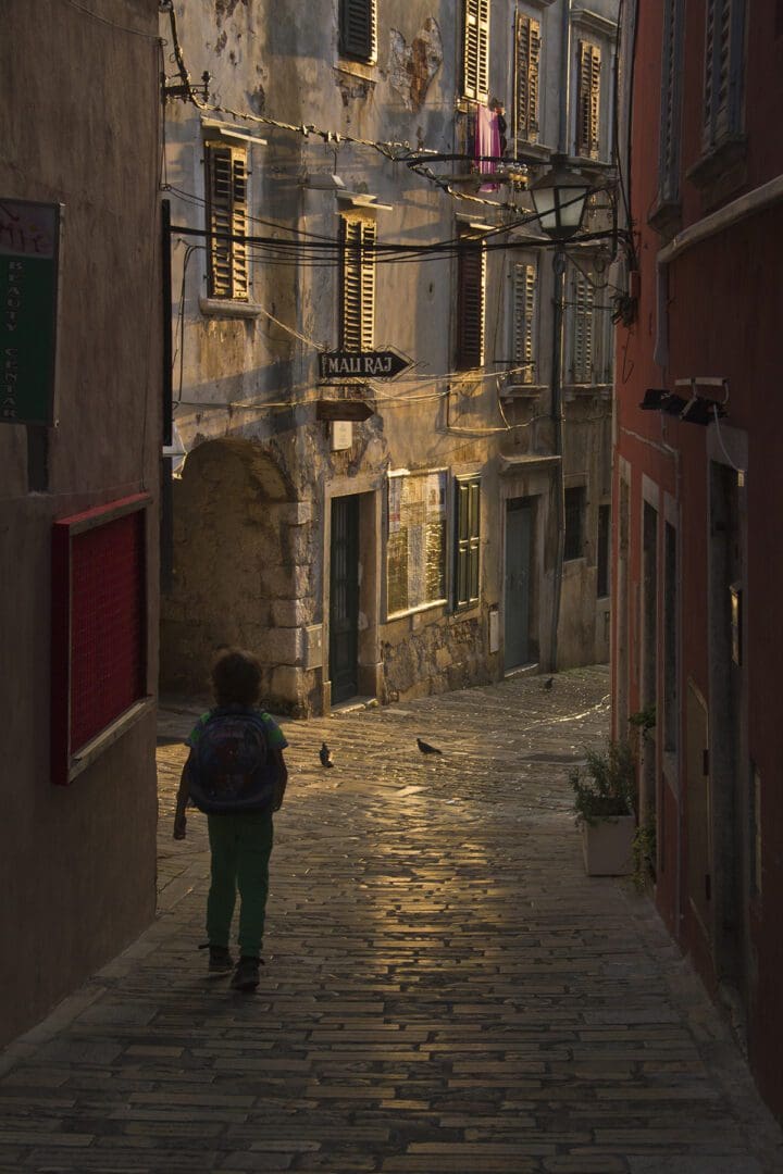 A child walking down a cobblestone street.
