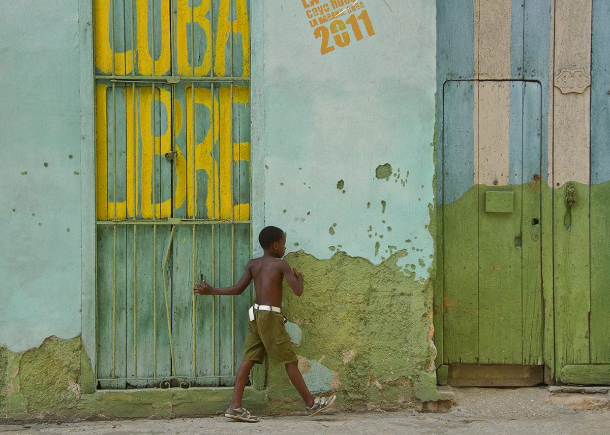 A boy walking past a building with a sign that says cuba libre.