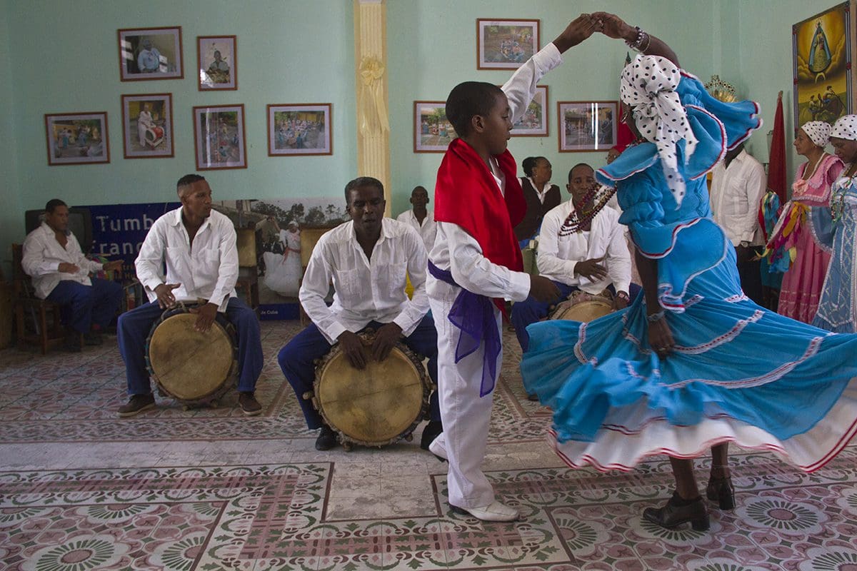 A group of people dancing in front of a drum.
