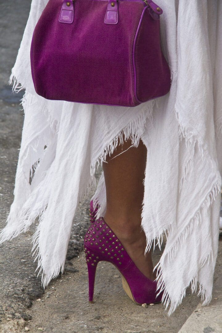 A woman wearing a white dress and a purple purse.