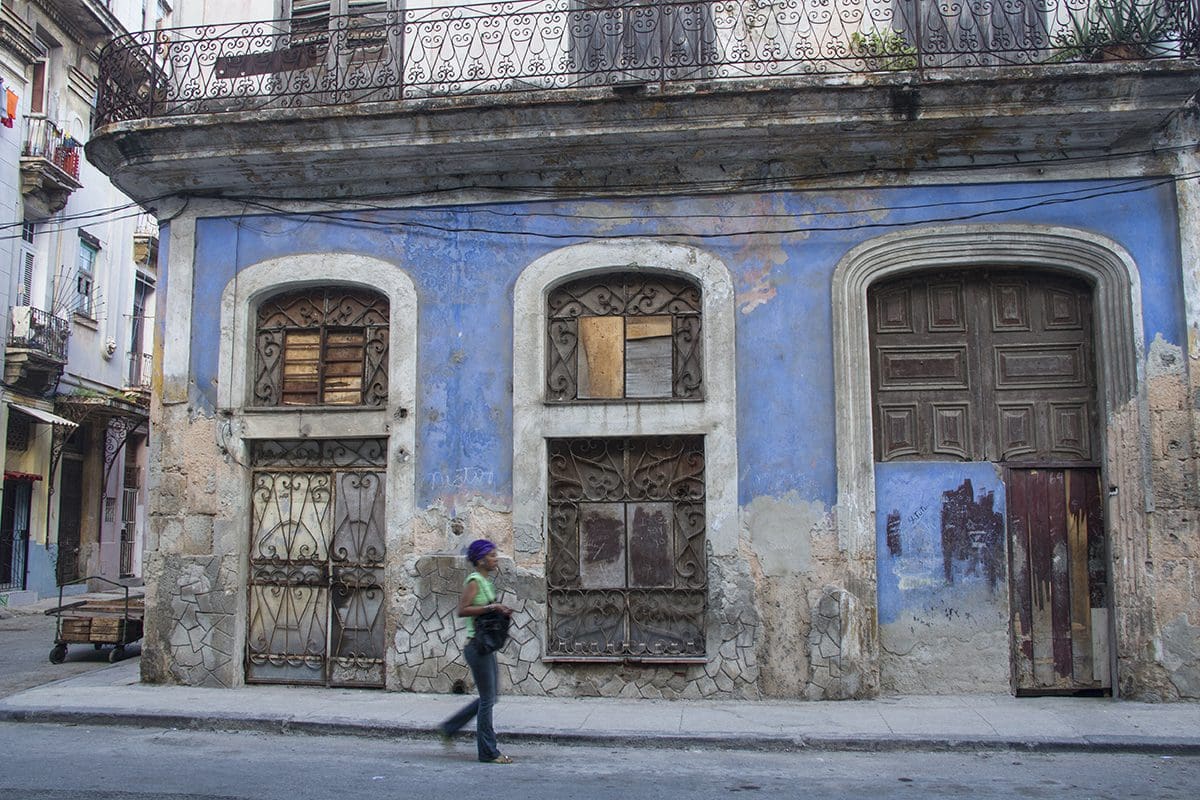 A woman walks past an old building in havana.