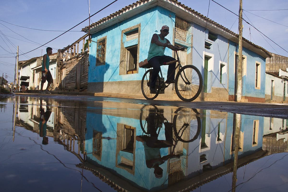 A man riding a bicycle in a puddle.