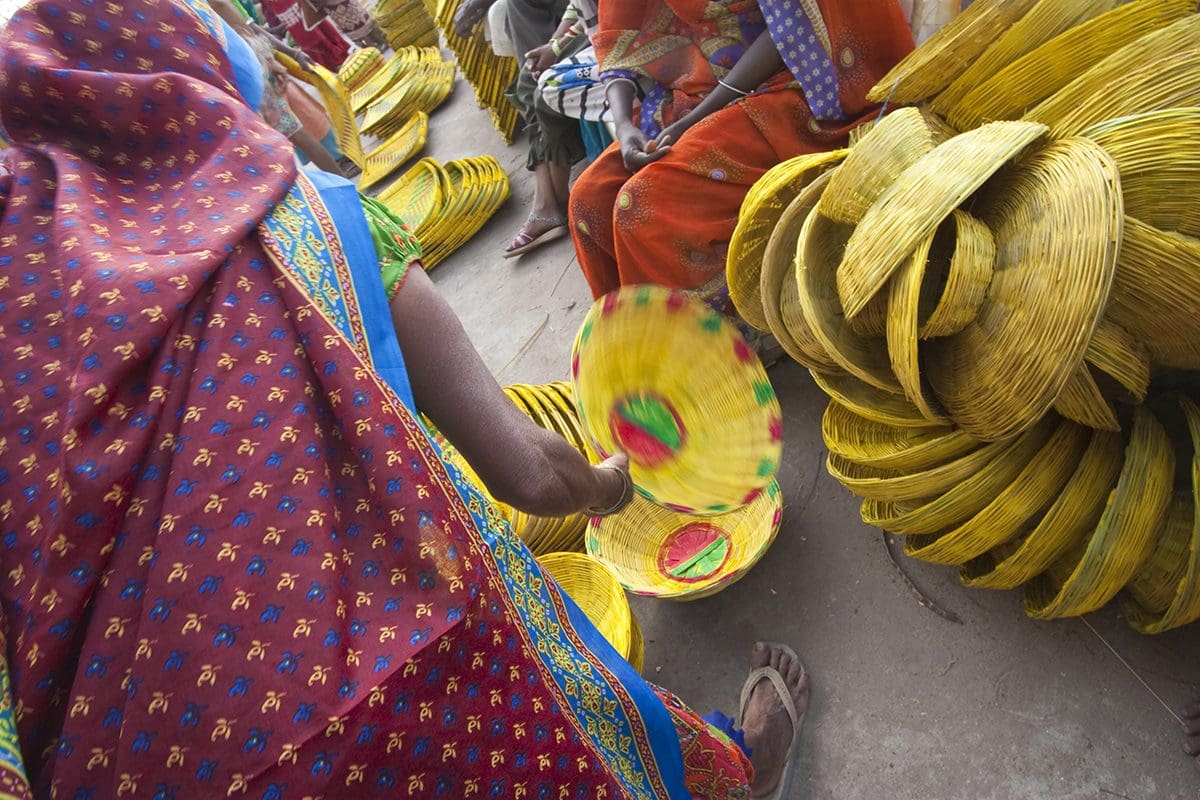 A woman in a sari is selling baskets in a market.