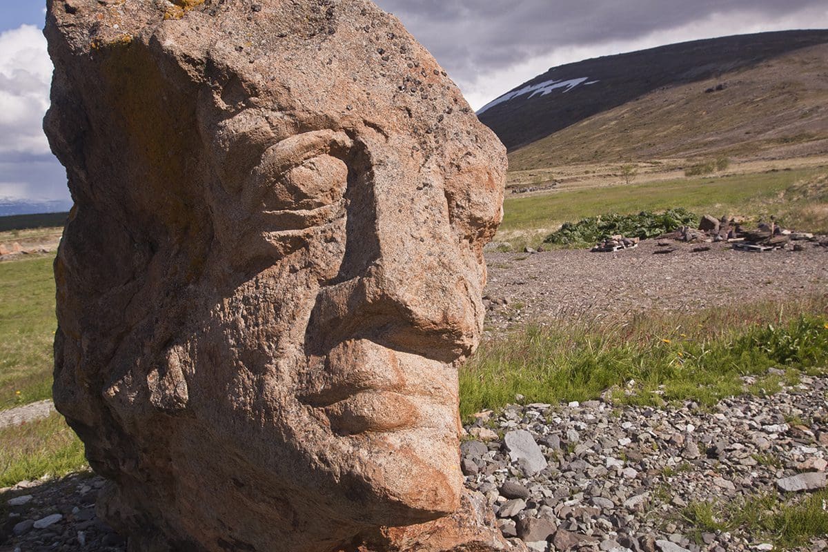 A large rock with a face on it in the middle of a field.