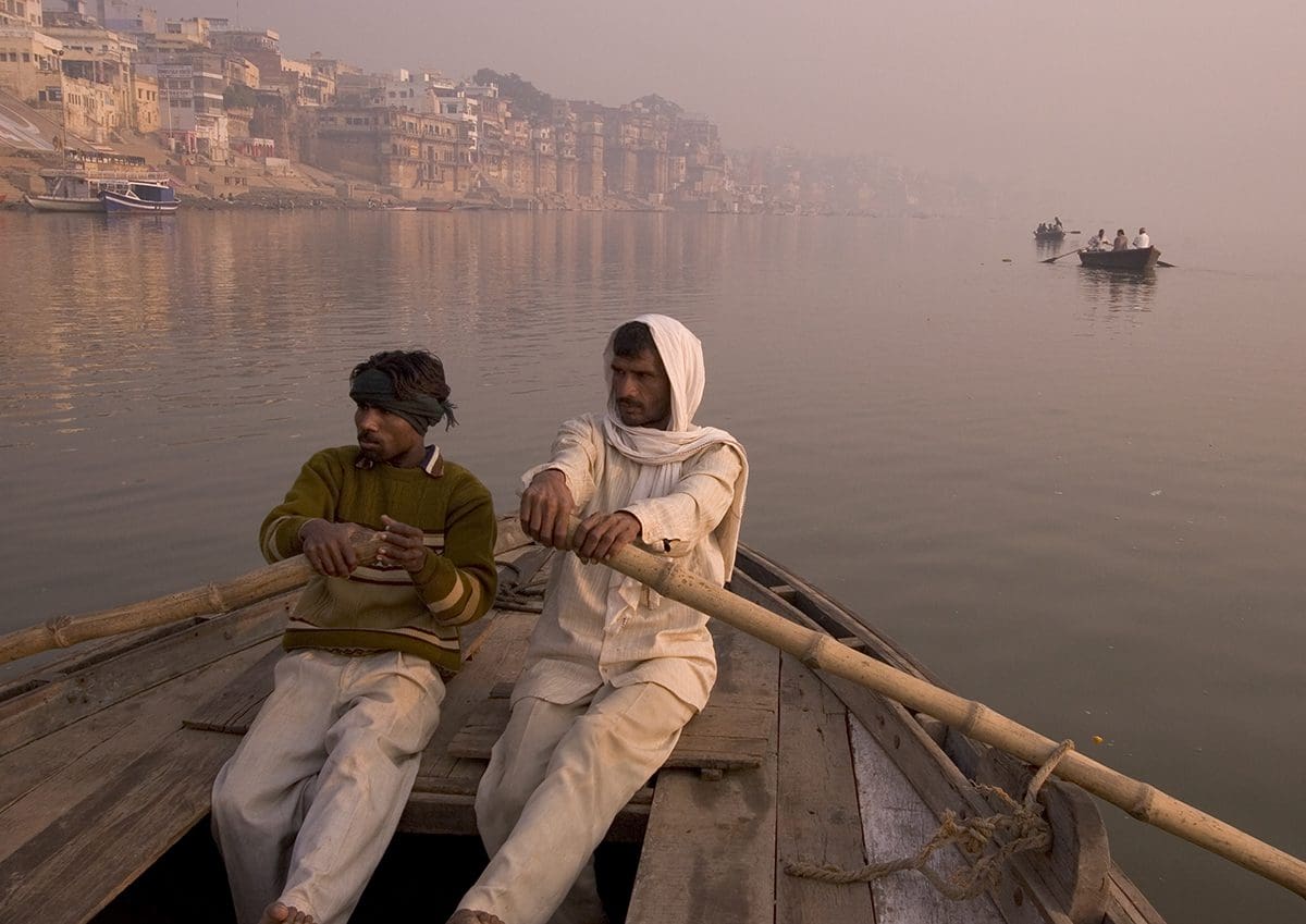 Two men in a boat on the ganges river, varanasi, india.