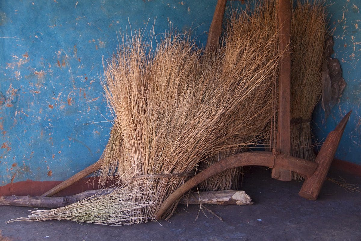 A pile of dry grass next to a blue wall.