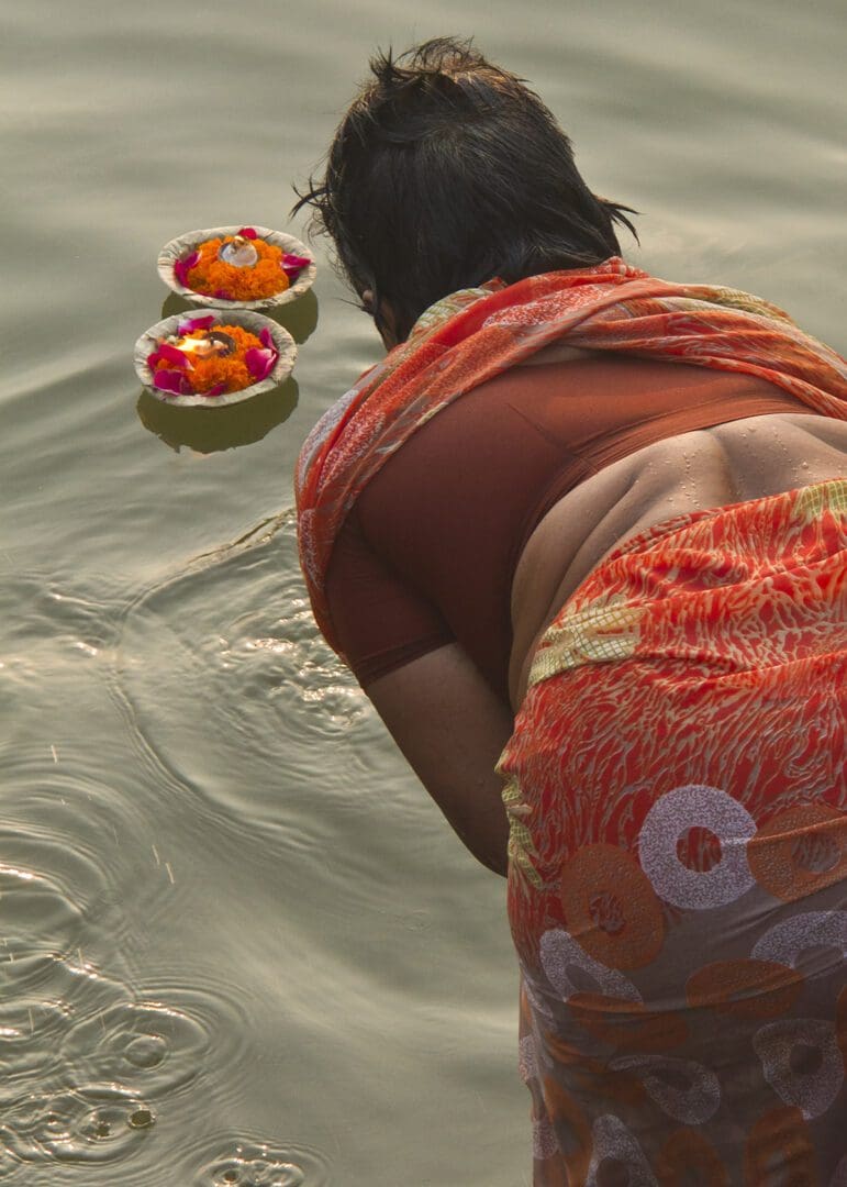 A woman in a sari is kneeling in the water.