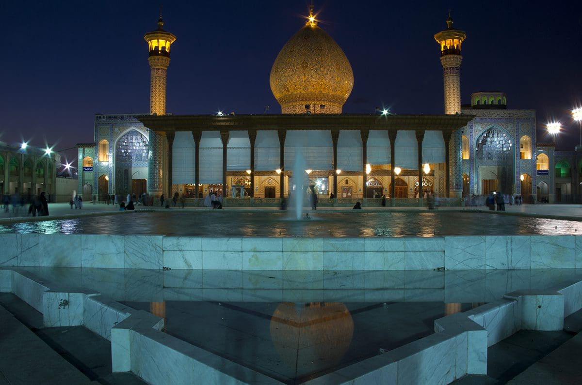 A mosque with a fountain in front of it at night.