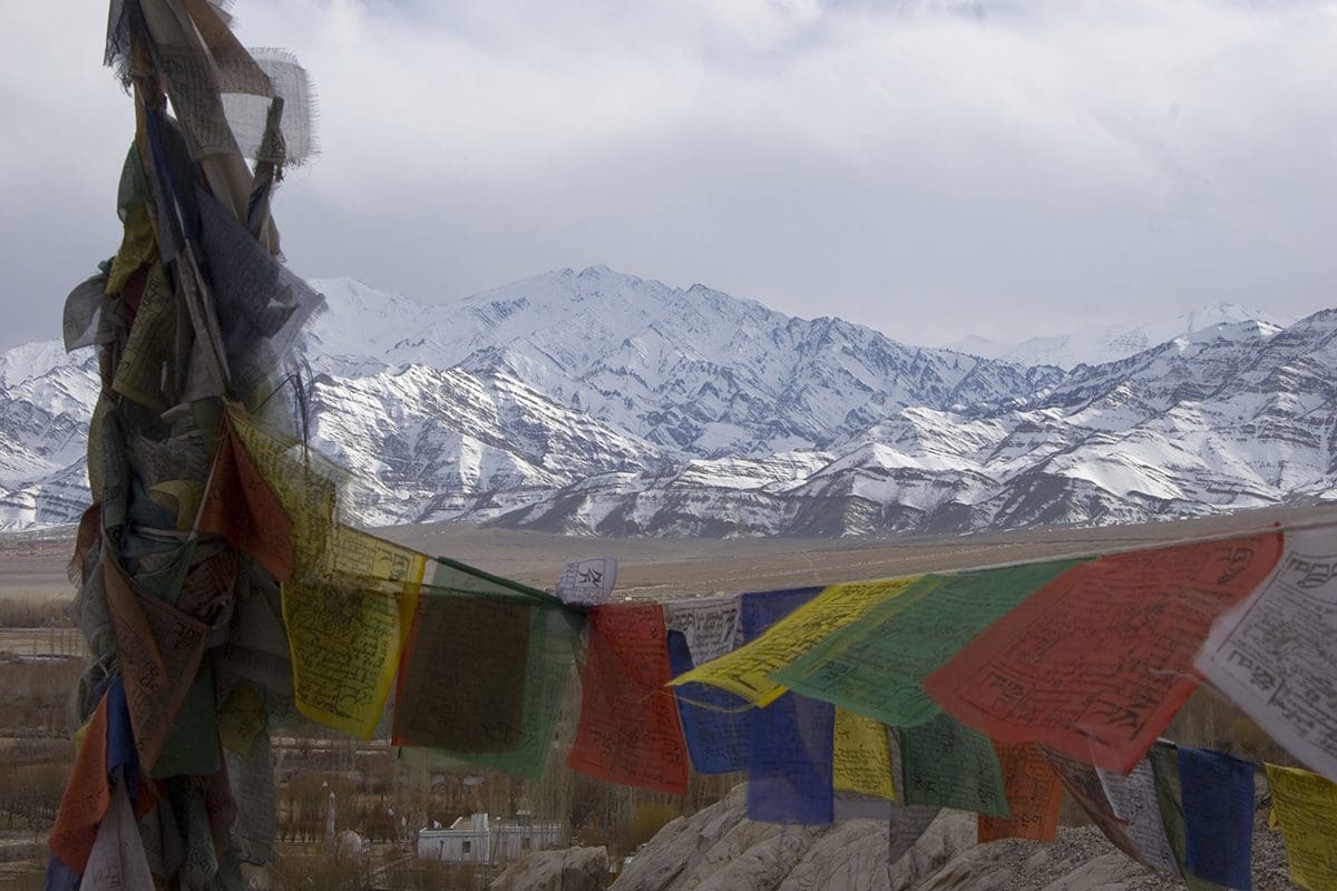 Prayer flags in front of snow capped mountains.