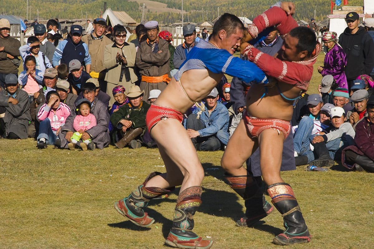 Two men fighting in front of a crowd.