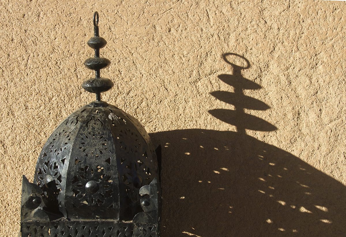 A metal lantern on a tan wall.