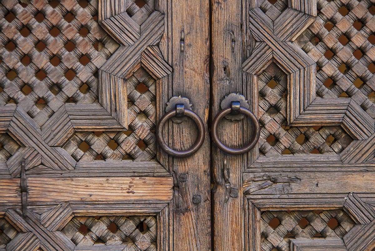 A wooden door with a metal ring on it.