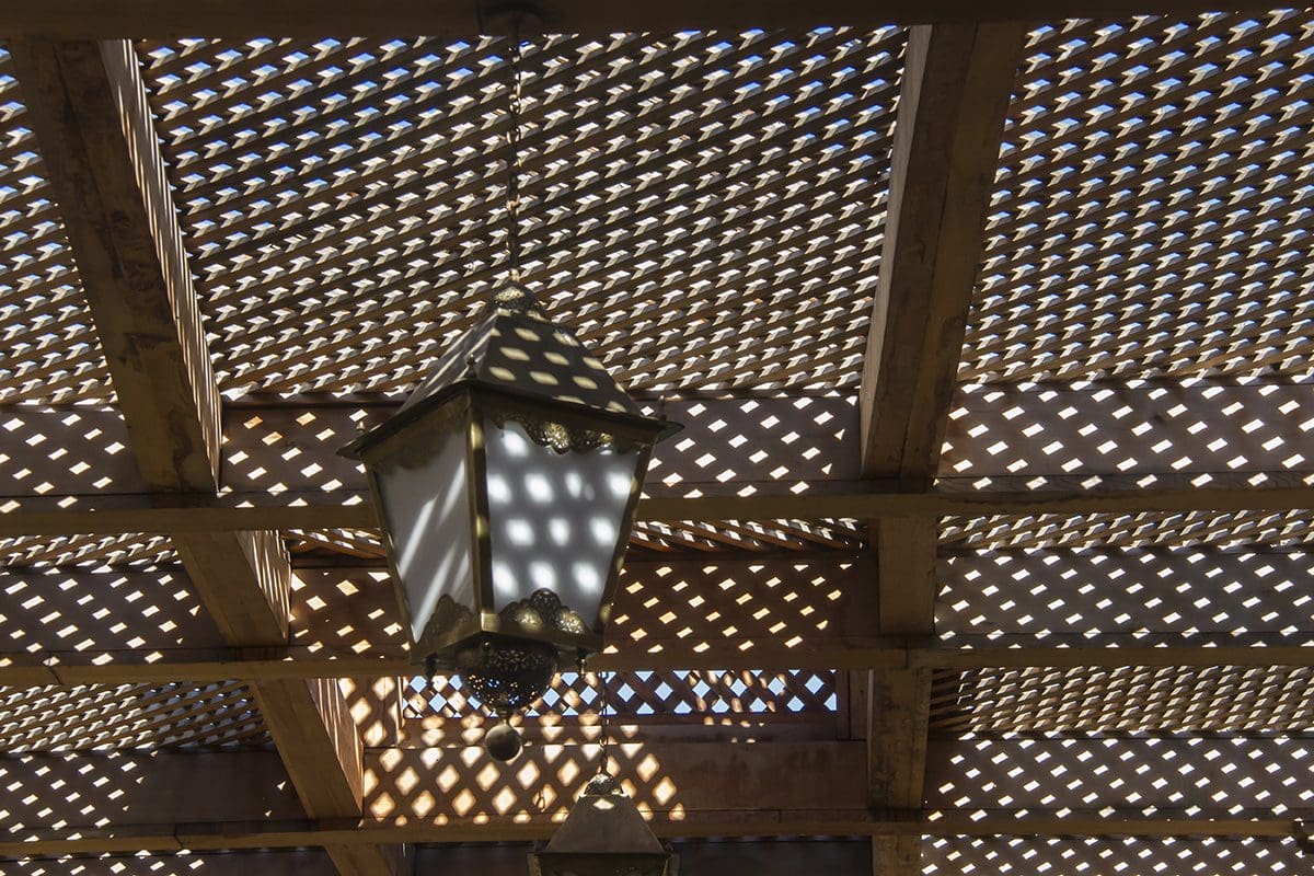 A wooden pergola with a light hanging from it.