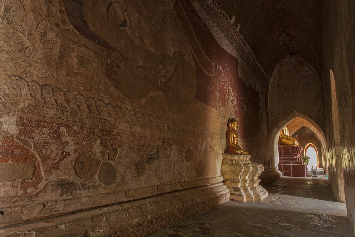 A hallway in a temple with a buddha in the middle.