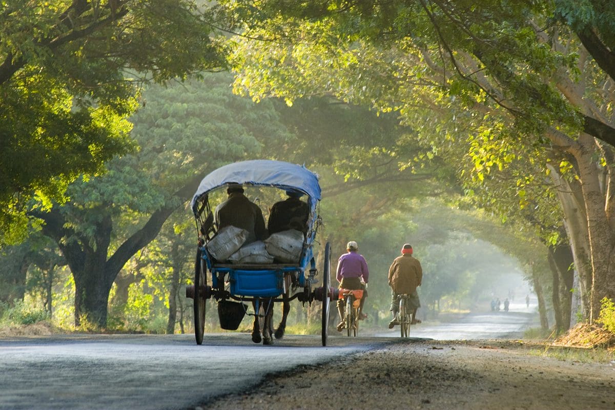 A group of people riding a rickshaw down a road.