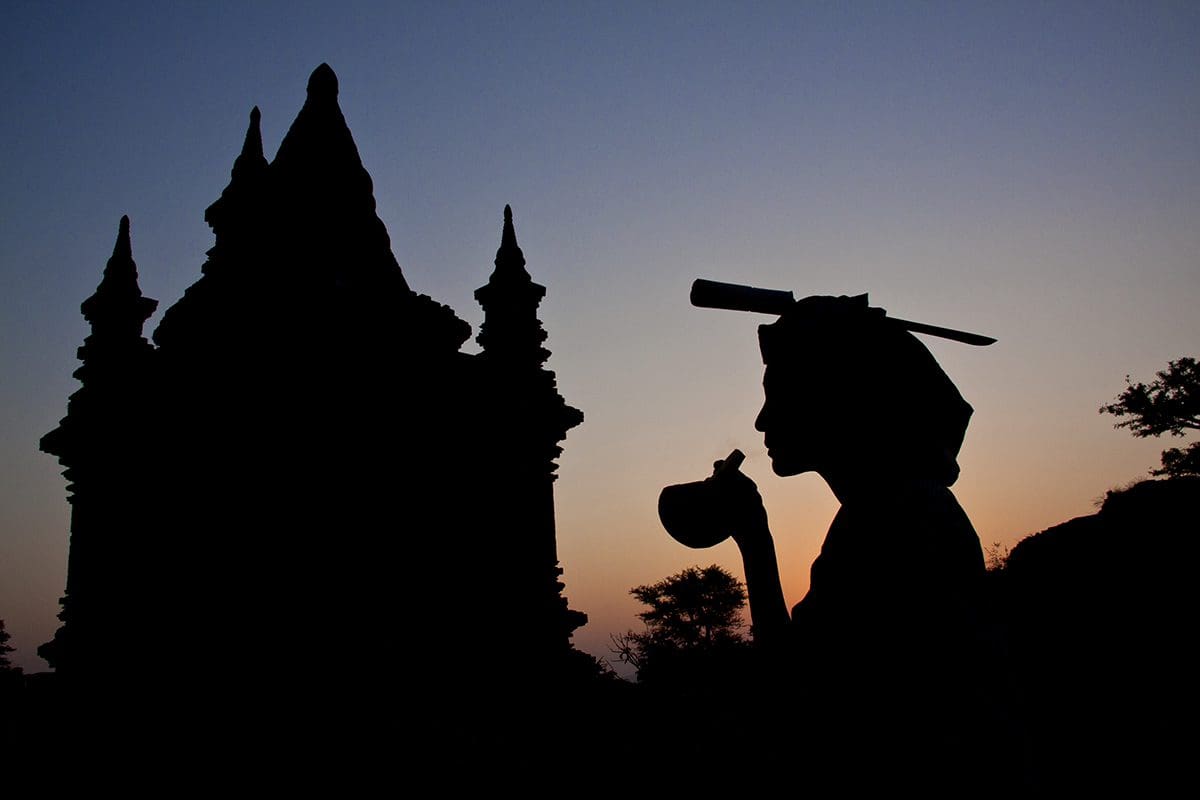 Silhouette of a man in front of a temple at sunset.