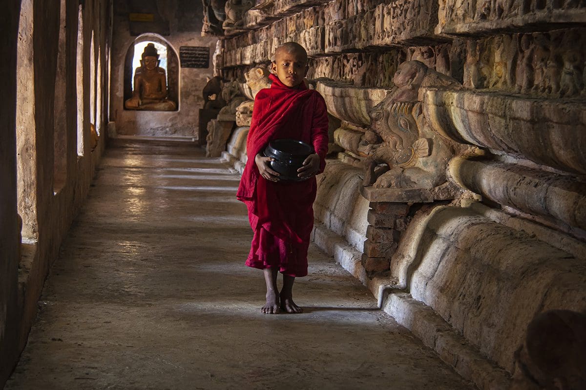 A buddhist monk holding a ball in a temple.