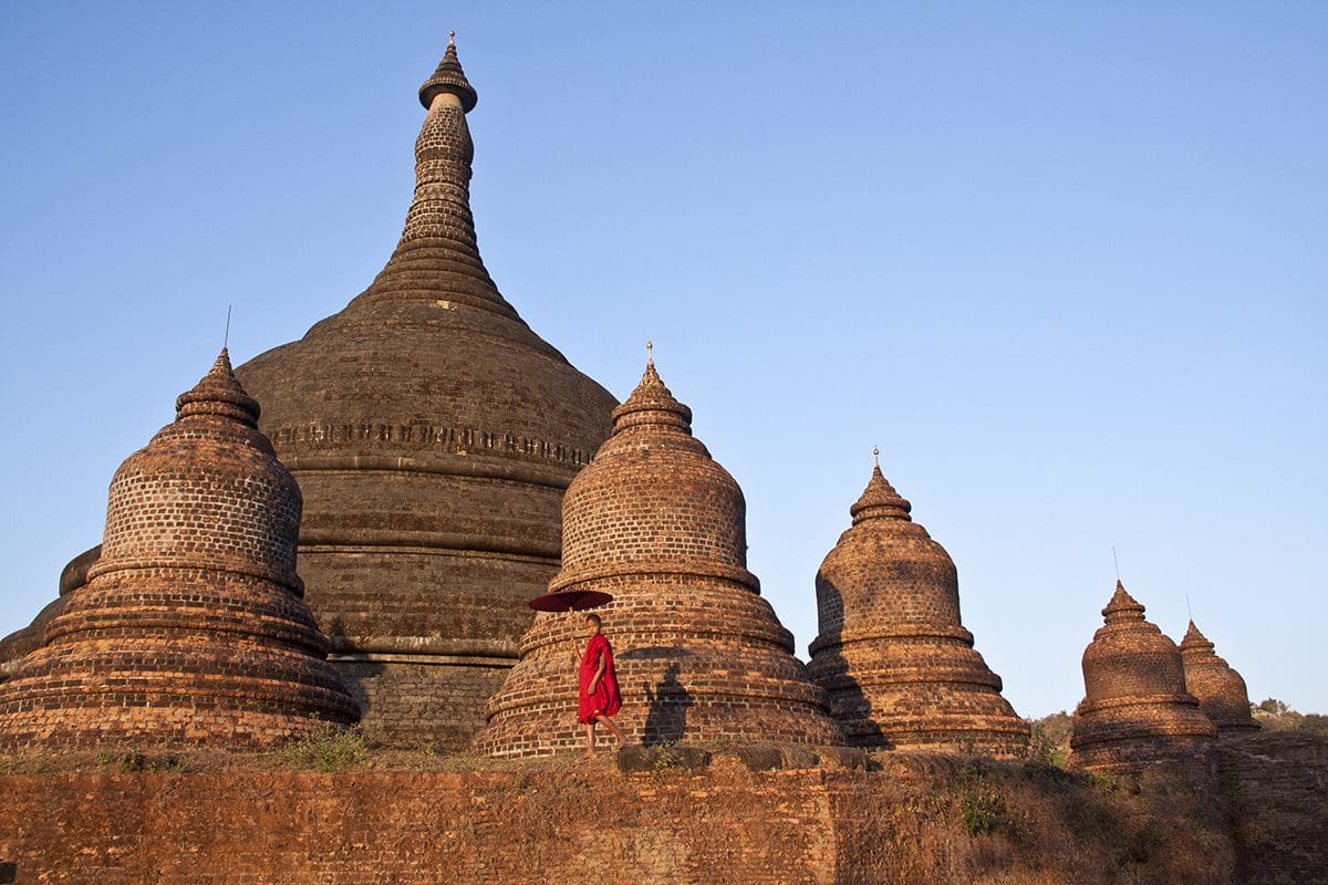 A man is standing in front of a brick pagoda.