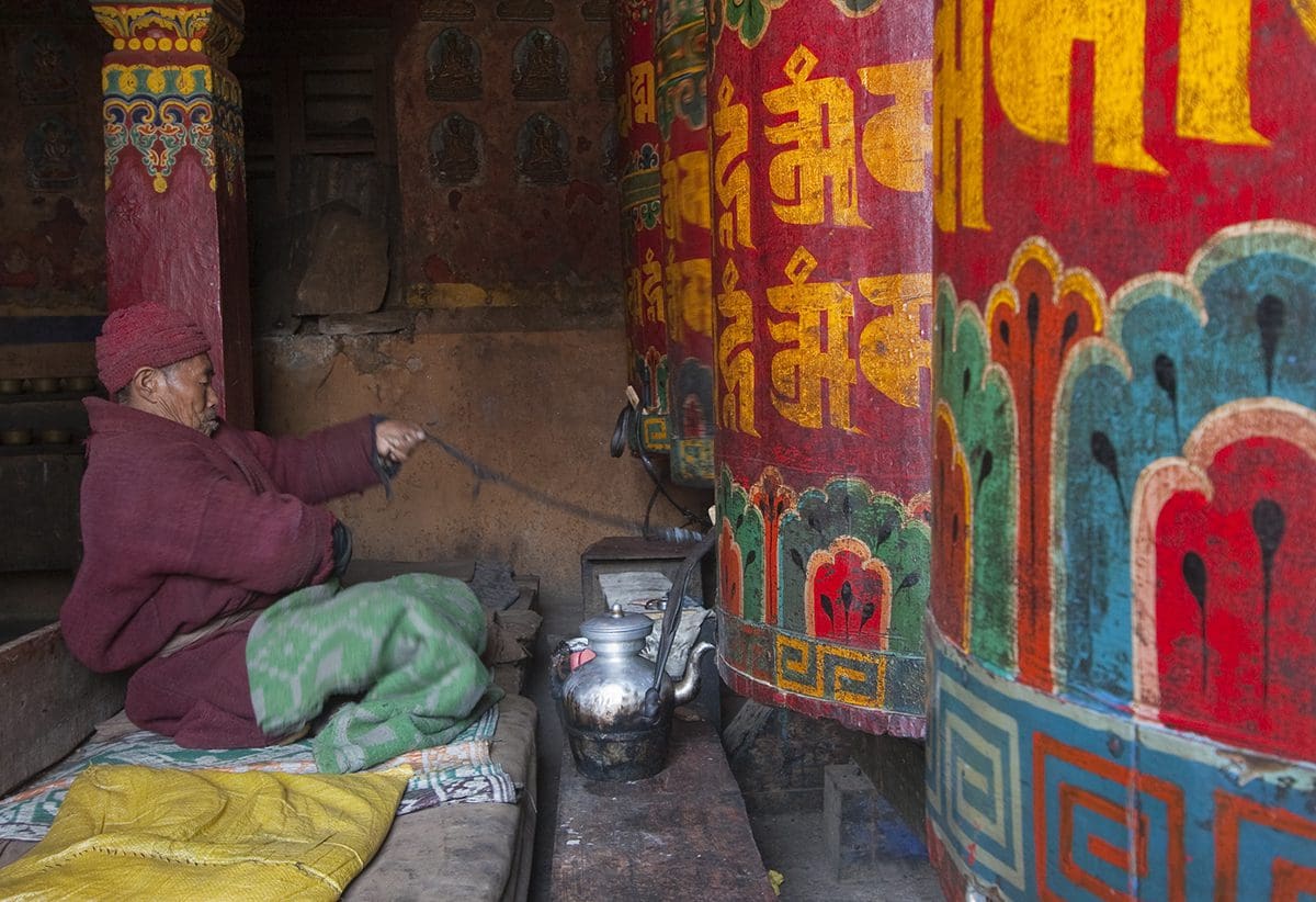 A man in a red robe is making tea in a buddhist temple.