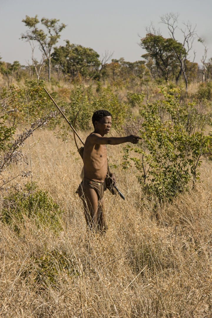 A man is standing in a field with a bow and arrow.