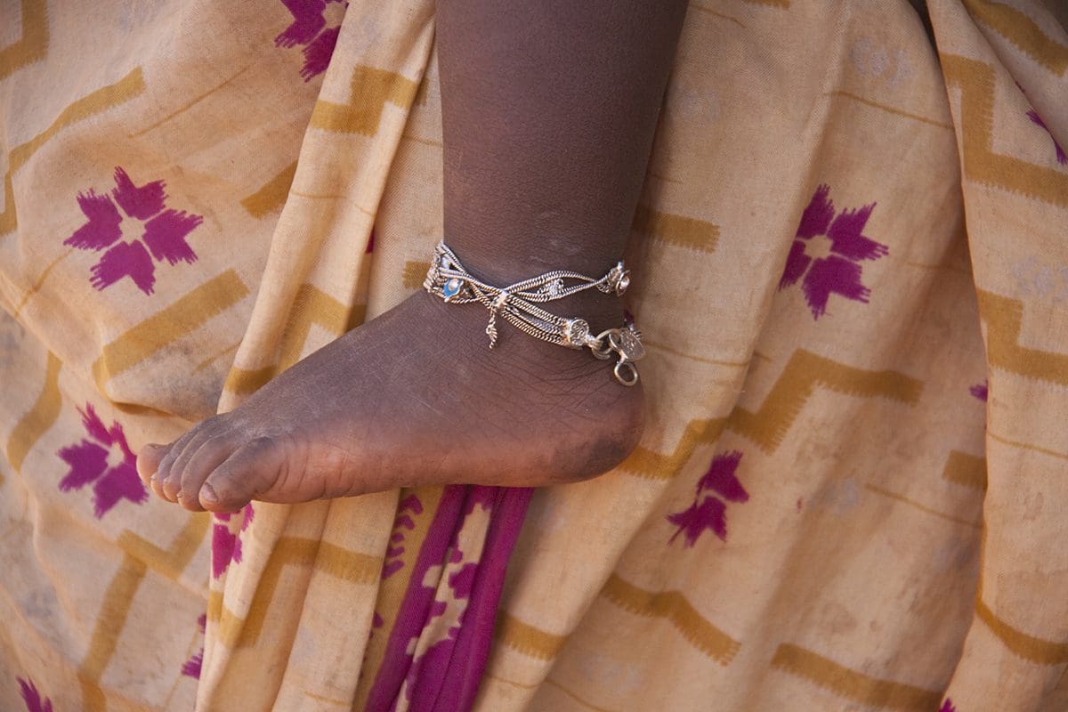 A woman's foot with bracelets on it.