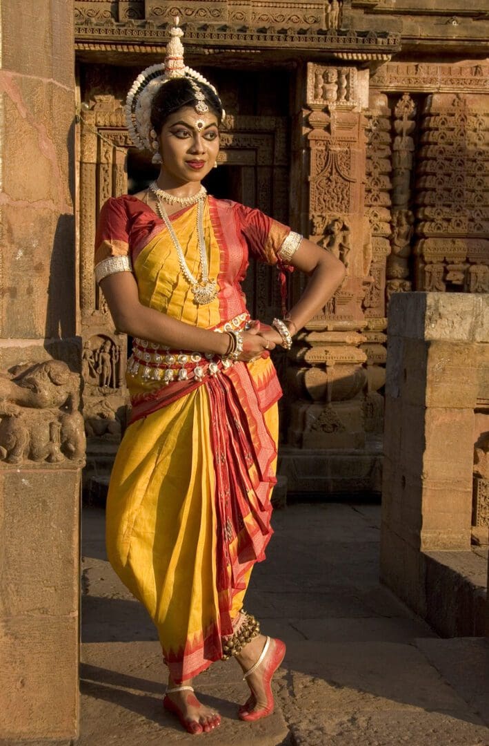 A woman in traditional indian attire posing in front of a temple.