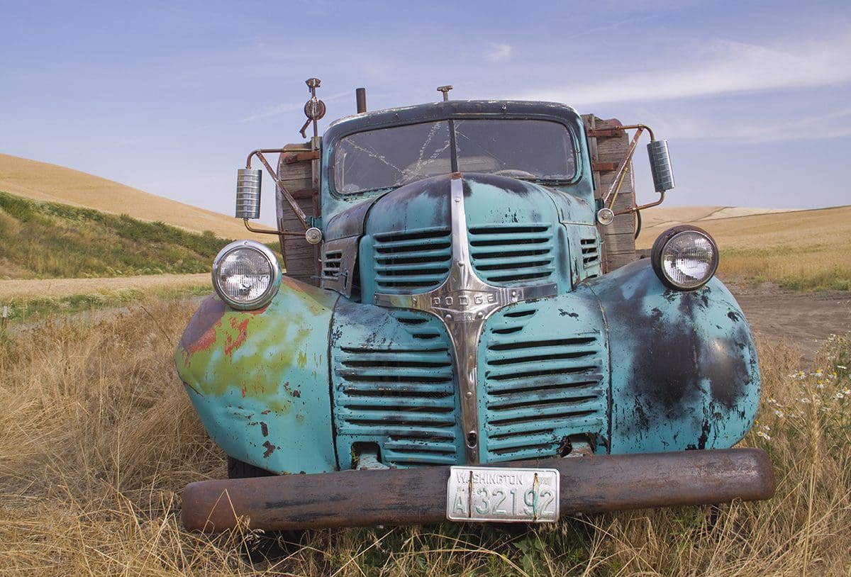 An old rusty truck parked in a field.