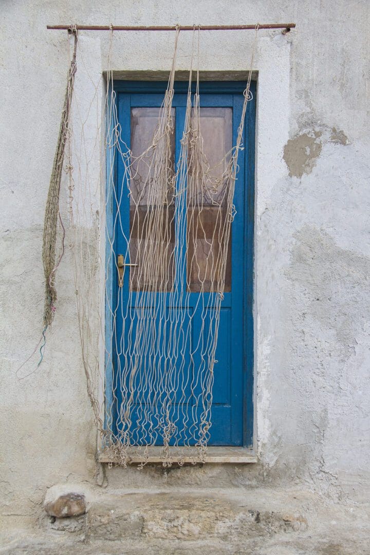 A blue door with fishing nets hanging from it.