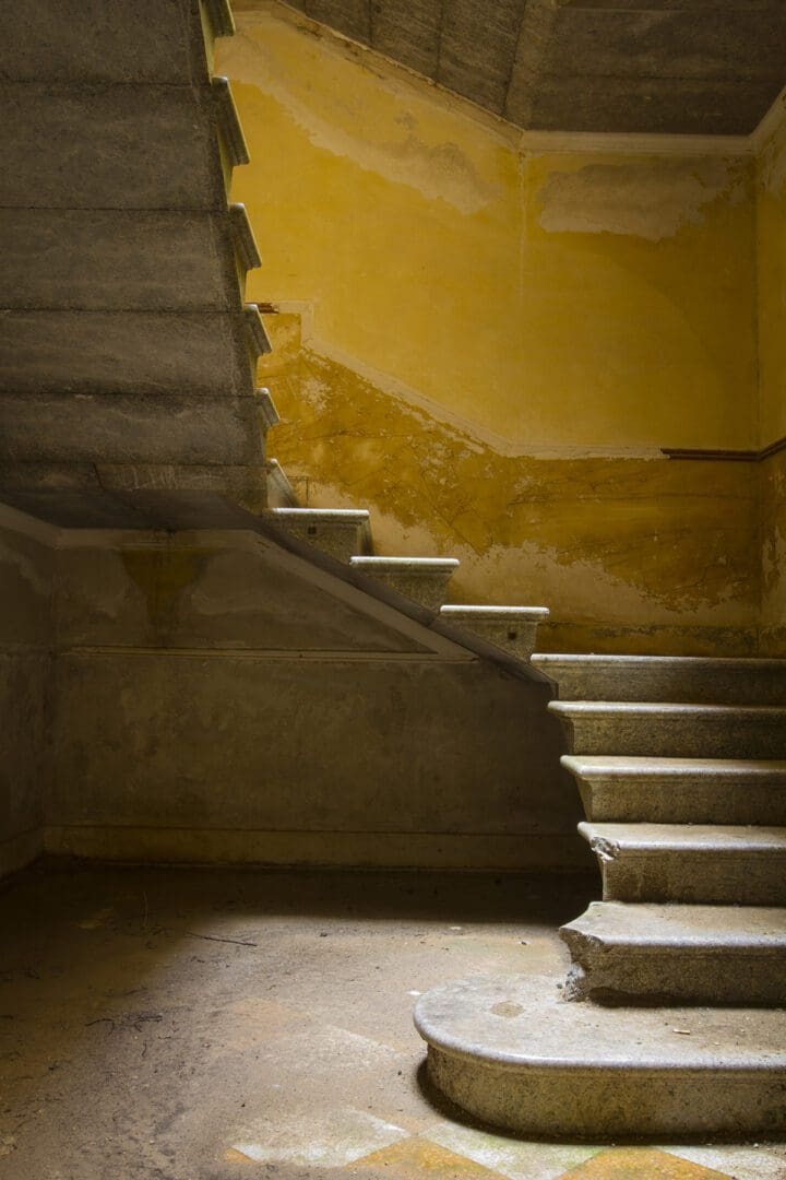 A staircase in an old building with a yellow wall.