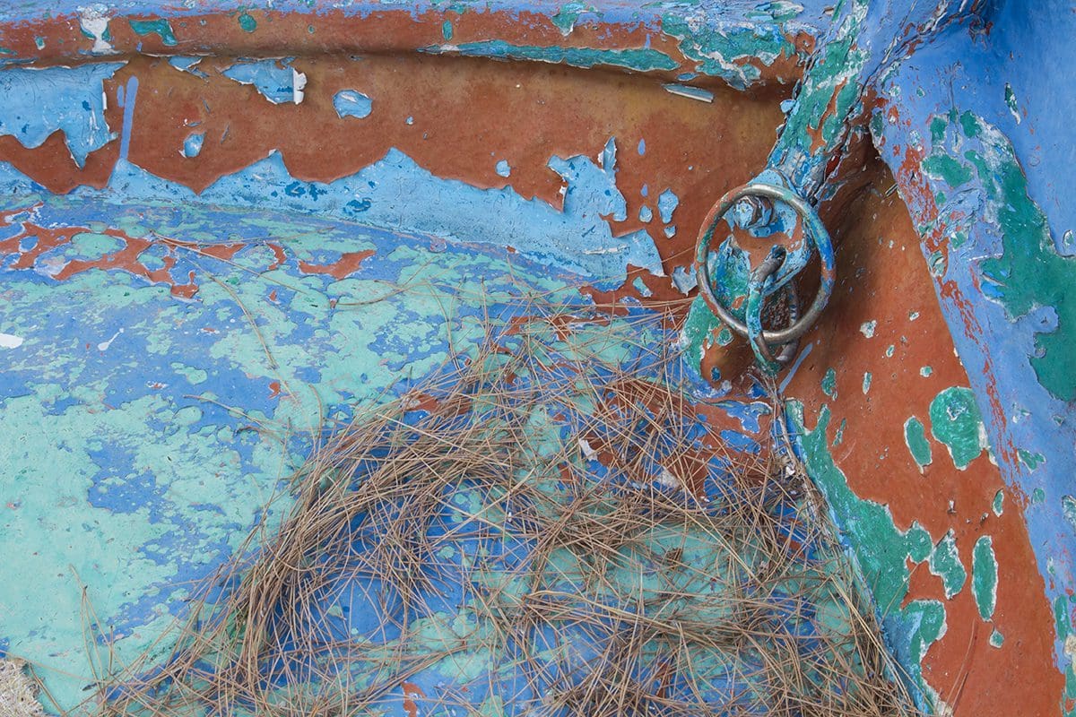 A blue and white boat with rust on it.