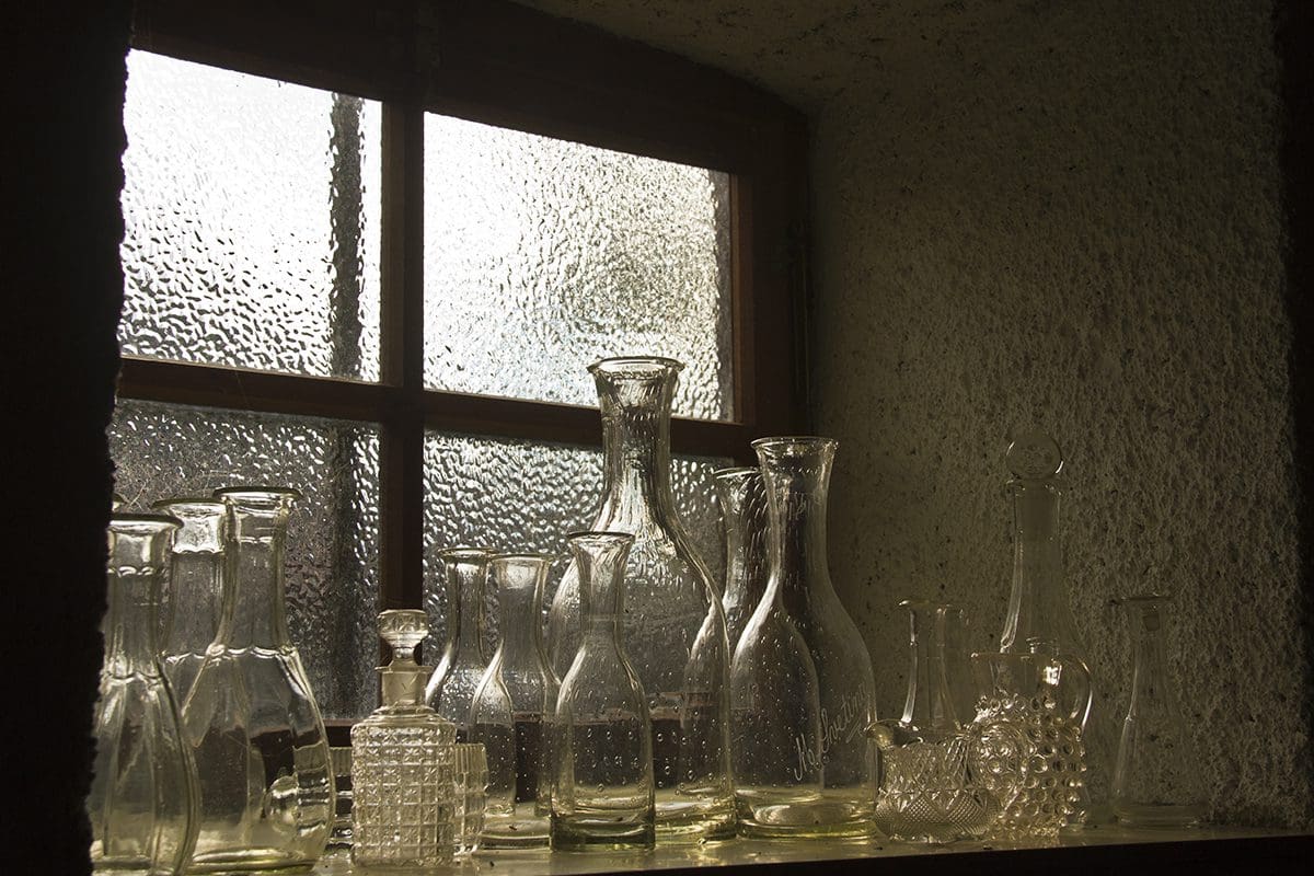 Glass bottles sitting on a window sill.