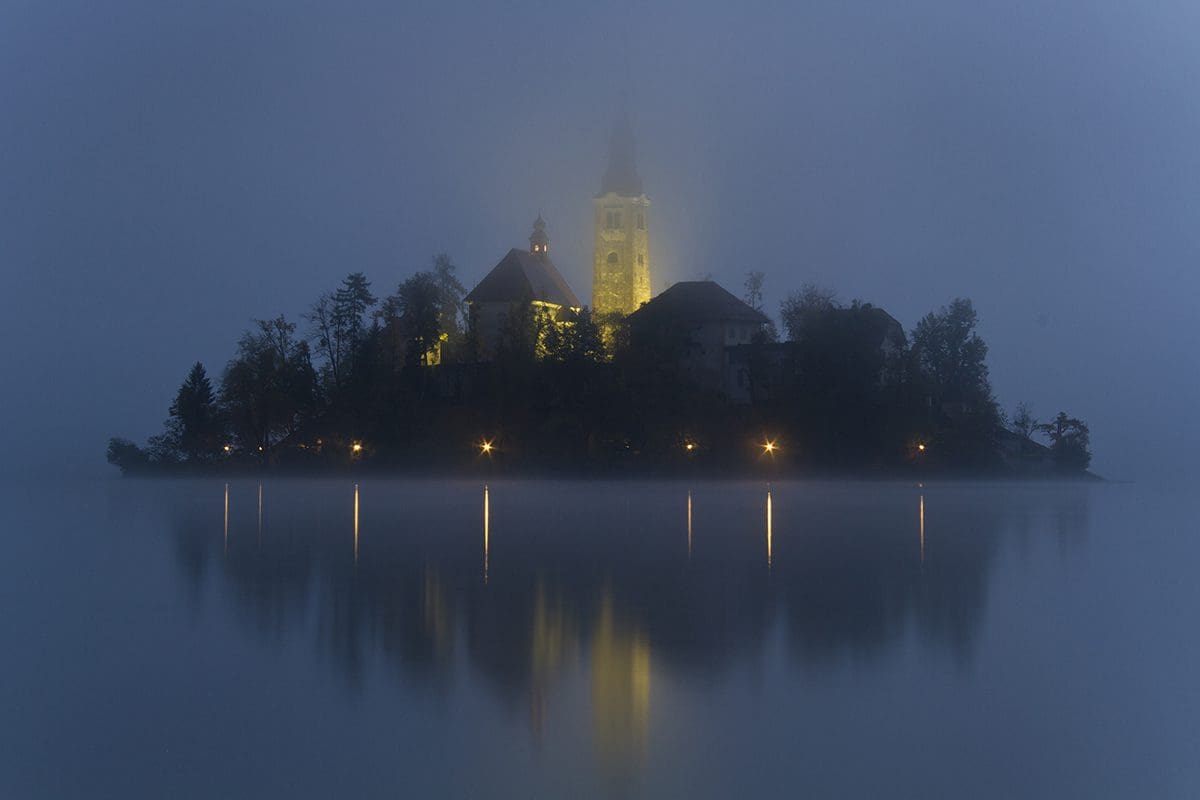 A small island with a church on it in the fog.